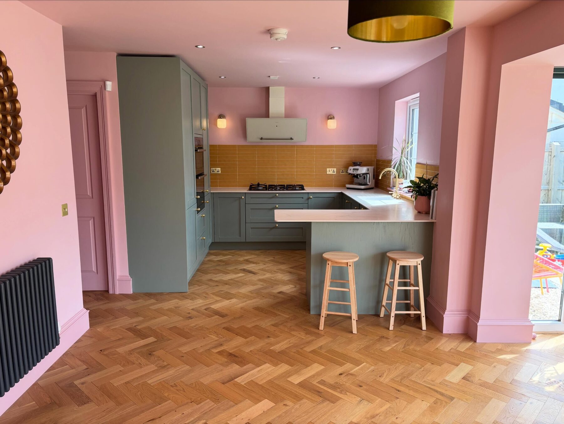 Renovated open plan kitchen with herringbone floor and pink walls